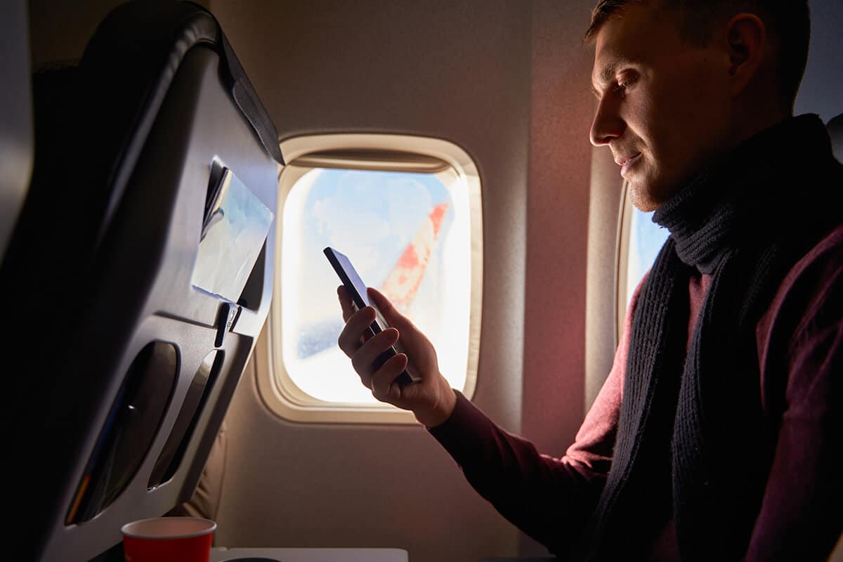 Man on airplane looking Tapping meditations on his phone to help overcome fear of flying
